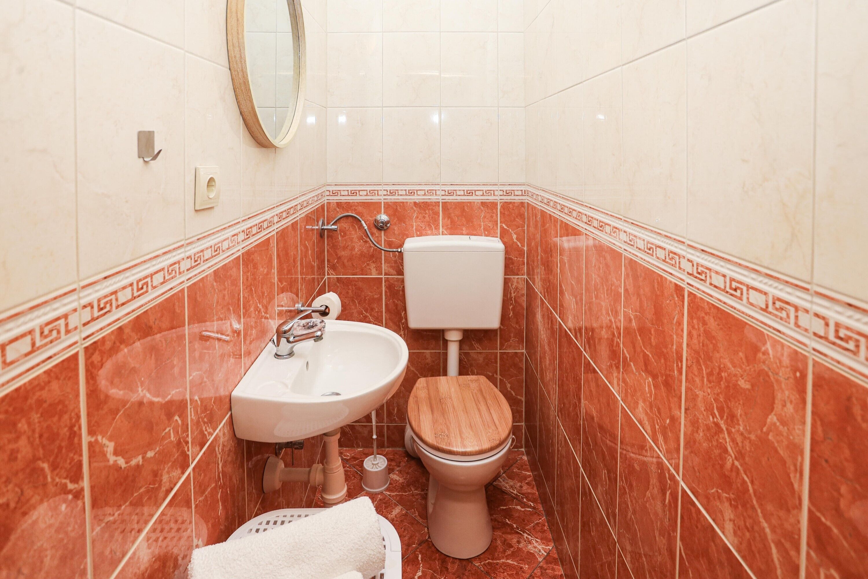 A small bathroom with a toilet, sink, and mirror.