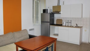 A compact kitchen with a wooden table, a built-in oven, and a microwave.
