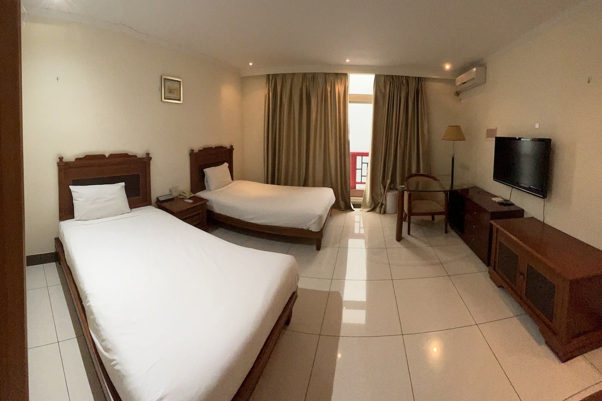 Habitación de hotel con dos camas, televisor, escritorio y silla.