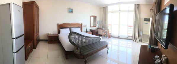 Una habitación de hotel con cama, mesita de noche, lámpara, televisión y vistas al exterior a través de la ventana.