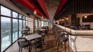 A modern bar with high ceilings, large windows, and a view of the city. - Lux Suites Le marc Luxury Apartments (Nairobi)