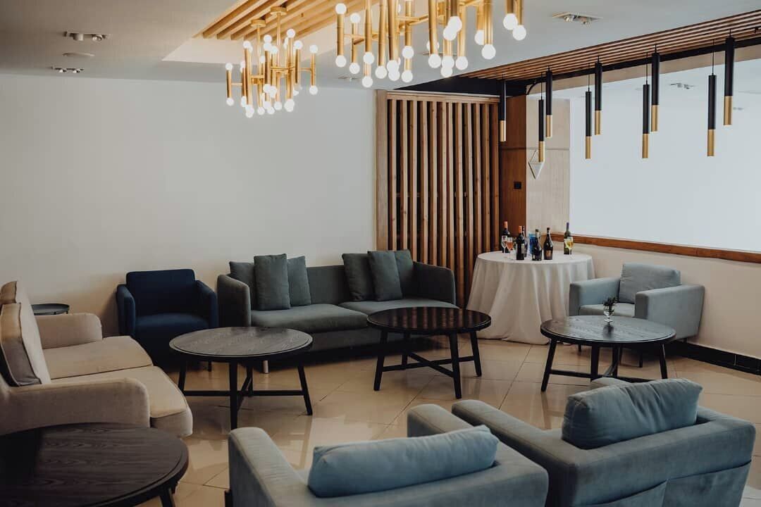 A modern lounge area with sofas, round tables, and hanging pendant lights.