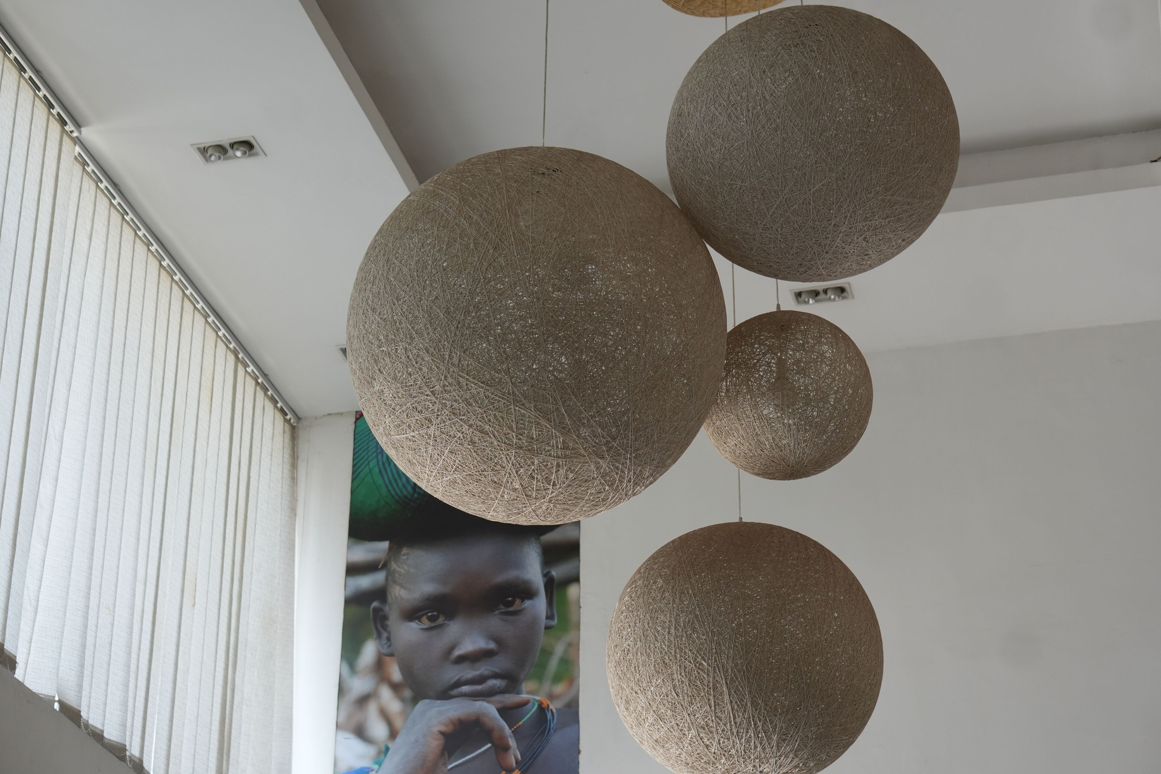 A ceiling with spherical light fixtures and a window with vertical blinds.