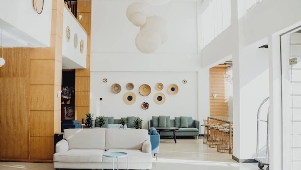 Un hall espacioso con un sofá blanco, un sillón azul y una pared de madera.