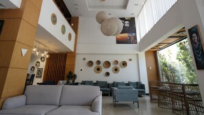 Una sala moderna con un sofá, dos sillones, un comedor con mesa y sillas, y un ventanal con vistas a zonas verdes.