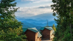 A row of log cabins with a mountain backdrop. - Enchanted View Lodge 3 Bedroom Cabin by RedAwning (Gatlinburg)