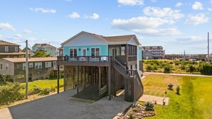 A two-story house with a balcony and a wooden deck. - Soundside Home with Elevator, Watersports Gear, Community Marina, Beach Nearby (Hatteras)