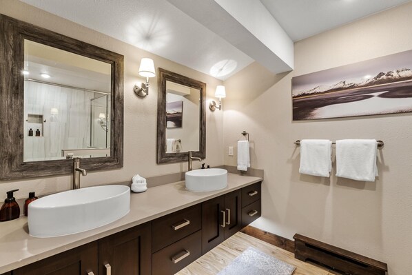 A modern bathroom with a large oval sink, two wall-mounted mirrors, and a painting of a landscape. - Short Walk to Slopes | Fireplace & Winter Shuttle (Steamboat Springs)