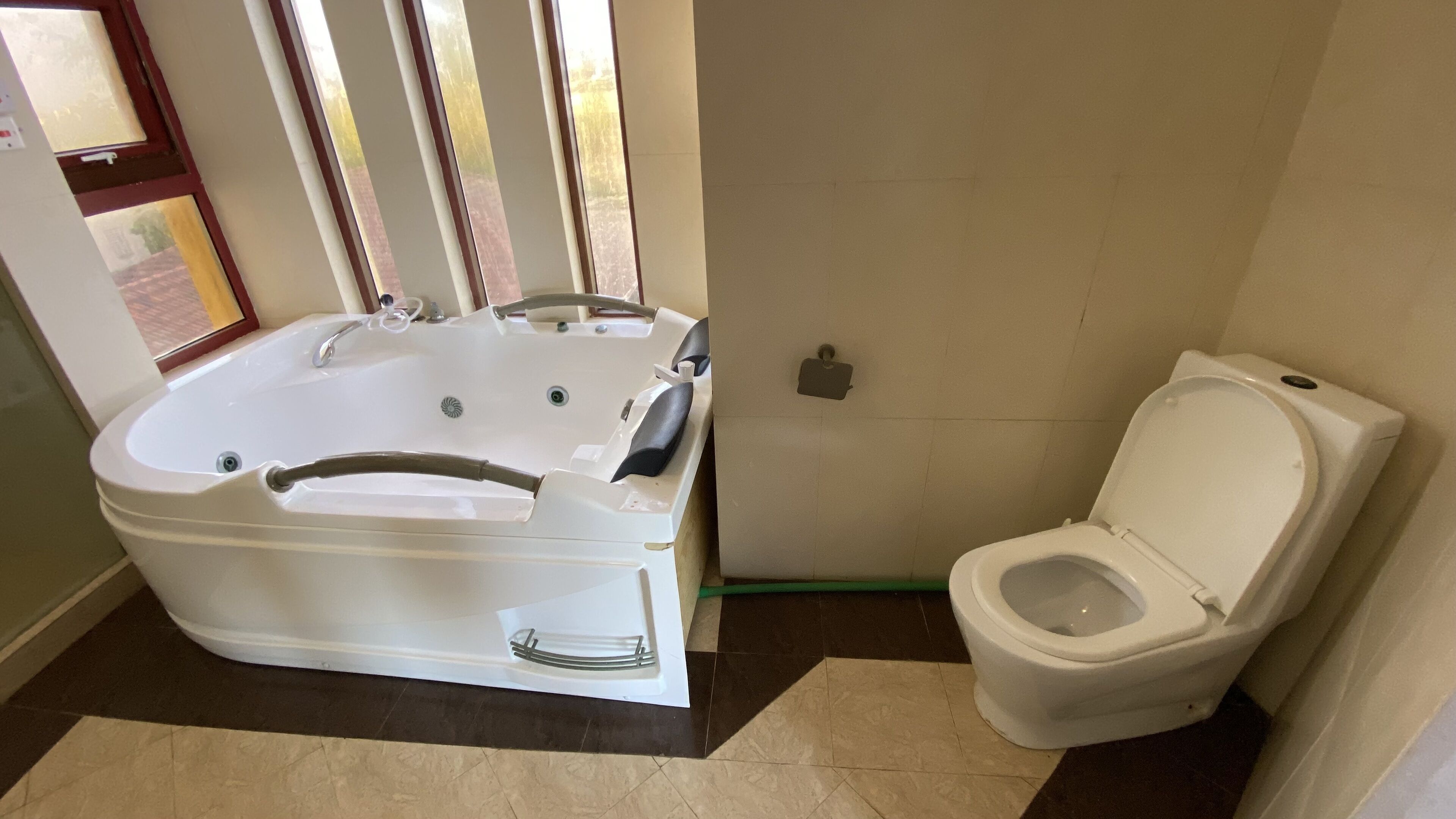 A bathroom with a bathtub, toilet, and a window.