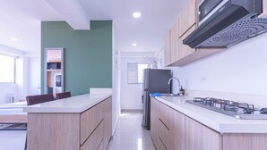 Eine moderne Küche mit hellen Holzschränken, einem Edelstahlkühlschrank und einem Gasherd.