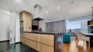 A modern kitchen with a central island, built-in oven, and stainless steel range hood. - Luxury apt El Tesoro with AC and city view (Medellín)
