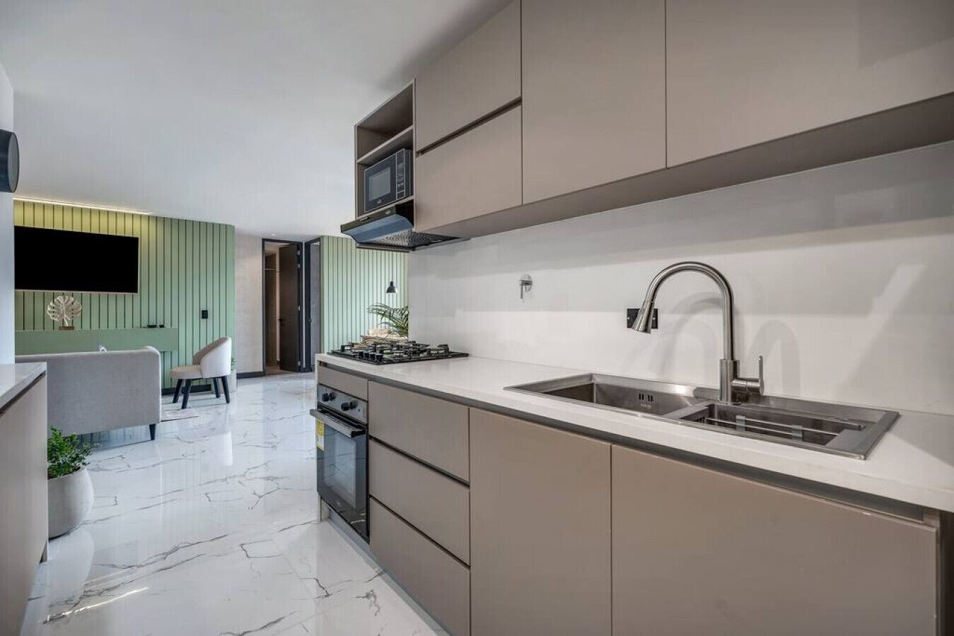 A modern kitchen with a stainless steel sink, a built-in oven, and a gas stove.