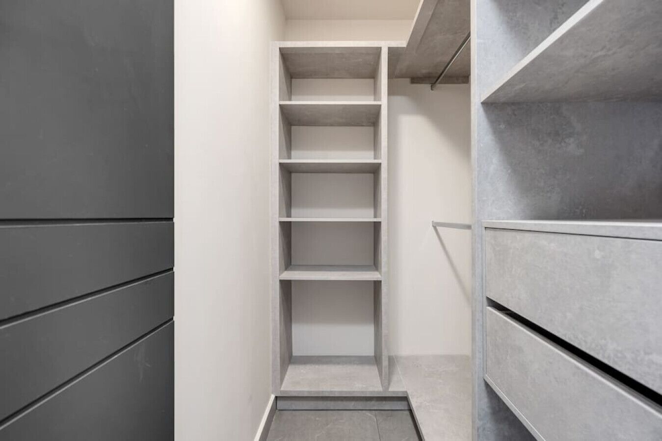 A narrow hallway with a built-in shelving unit on one side and a metal railing on the other.