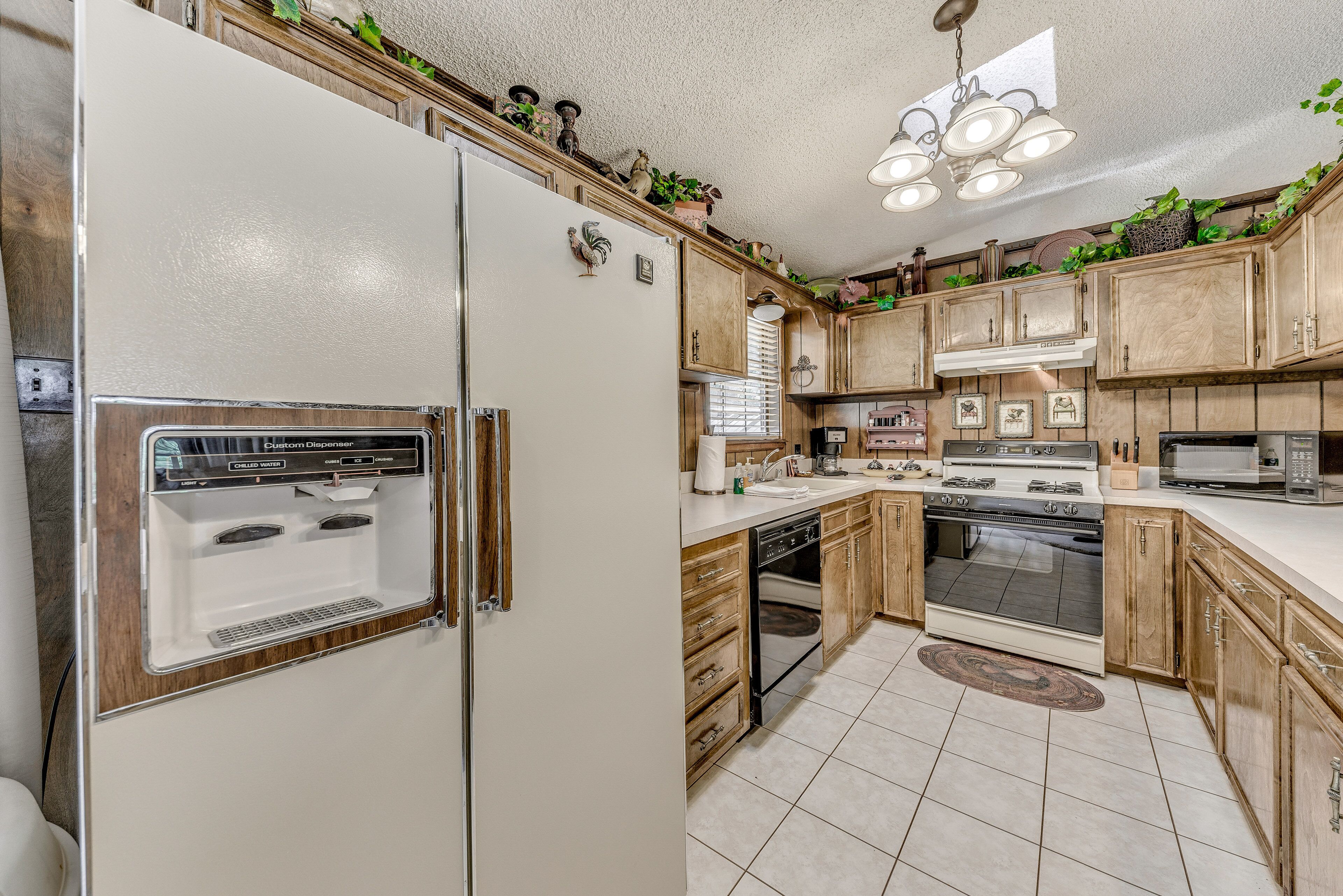 A kitchen with a refrigerator, oven, dishwasher, and a sink.