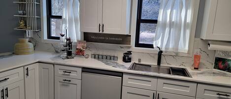 A modern kitchen with white cabinets, a marble countertop, a wine rack, and a sign that says "happiness is homemade."