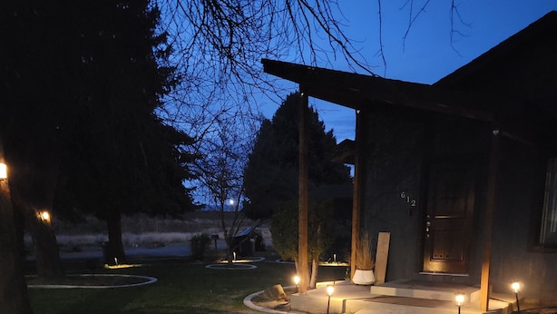 A pathway leading to a building with a covered porch and outdoor lighting.