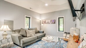 A modern living room with a grey sofa, a coffee table, and a TV mounted on the wall.