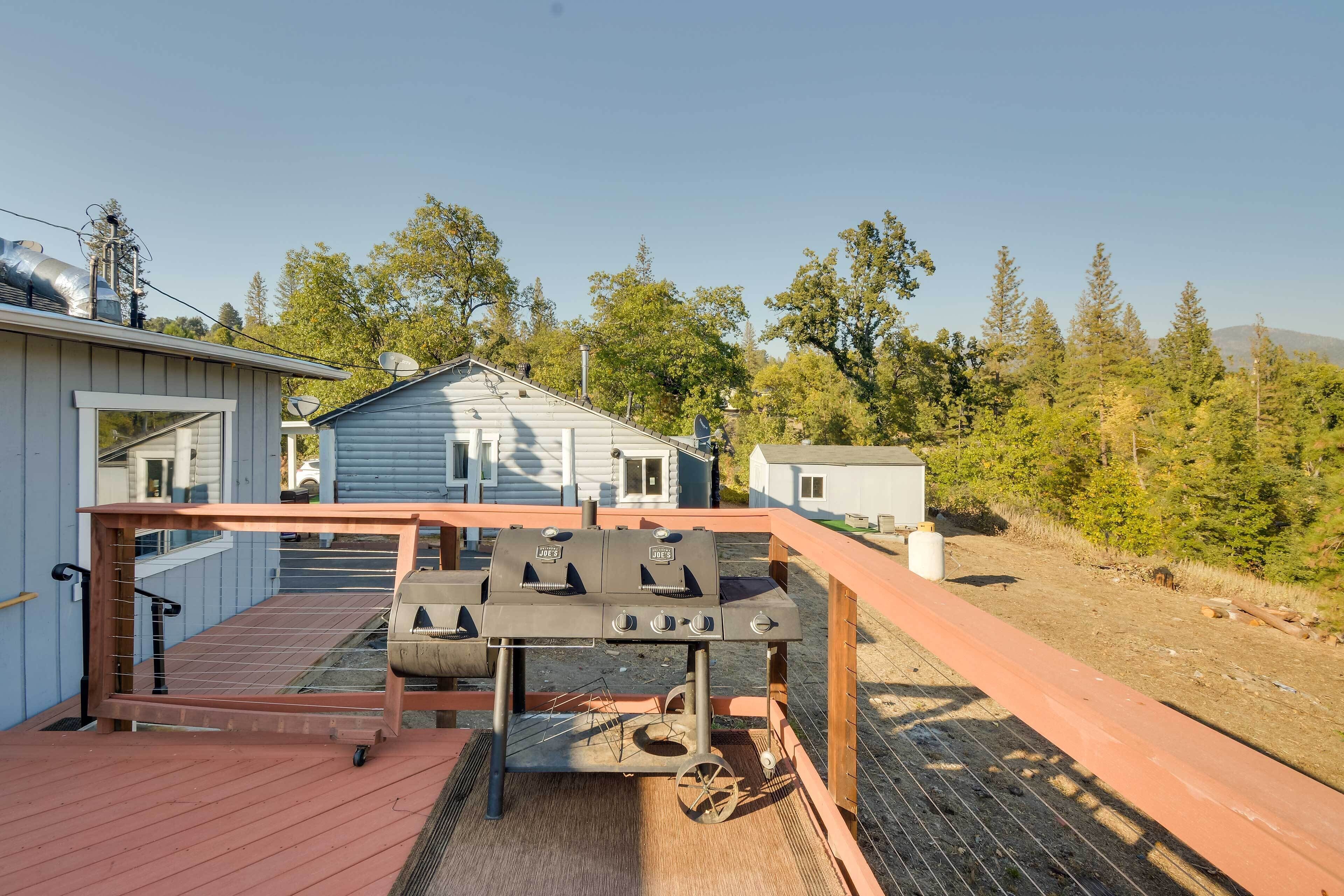 A wooden deck with a grill, a small shed, and a house in the background.