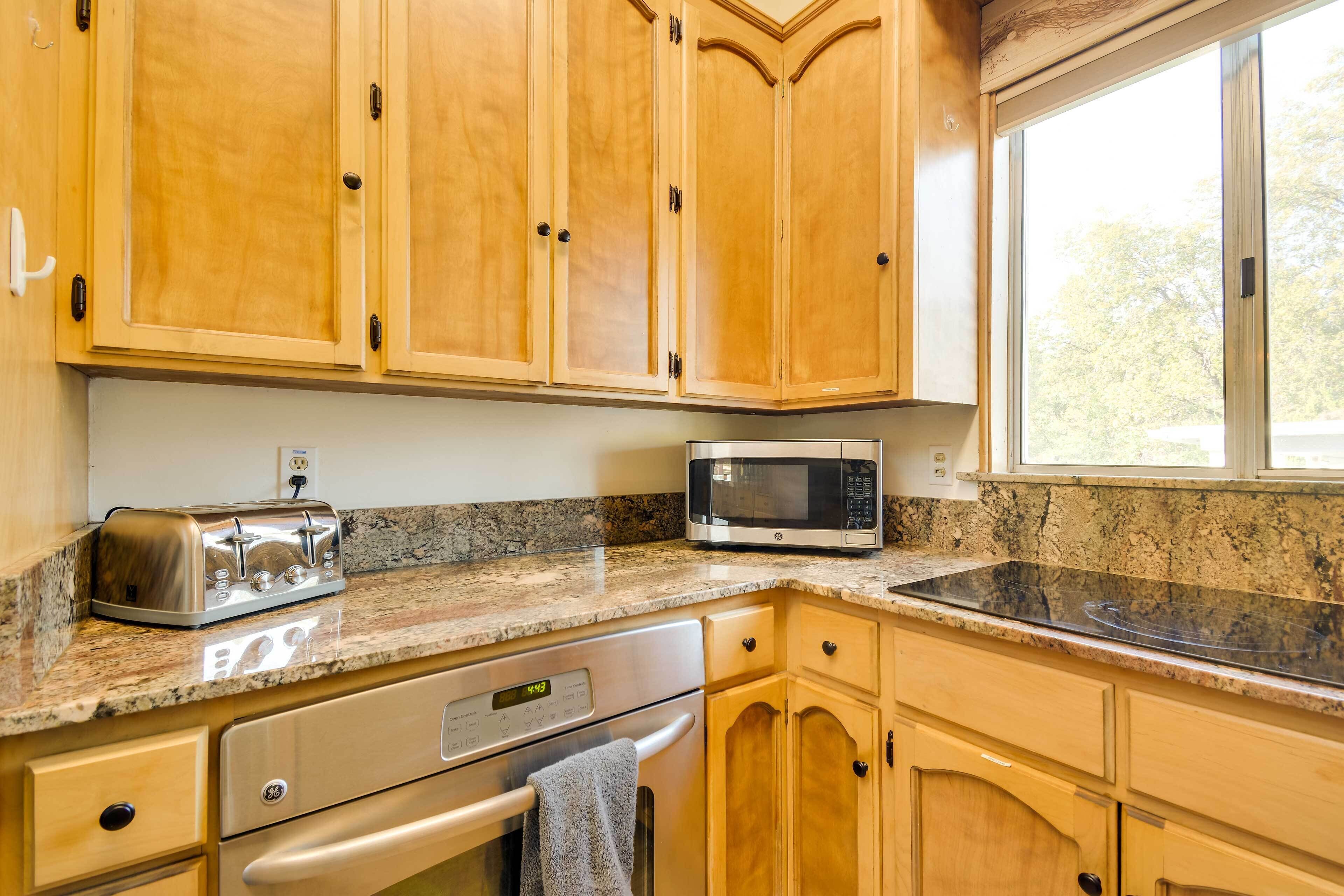 A kitchen with wooden cabinets, a stainless steel dishwasher, a microwave, and a granite countertop.