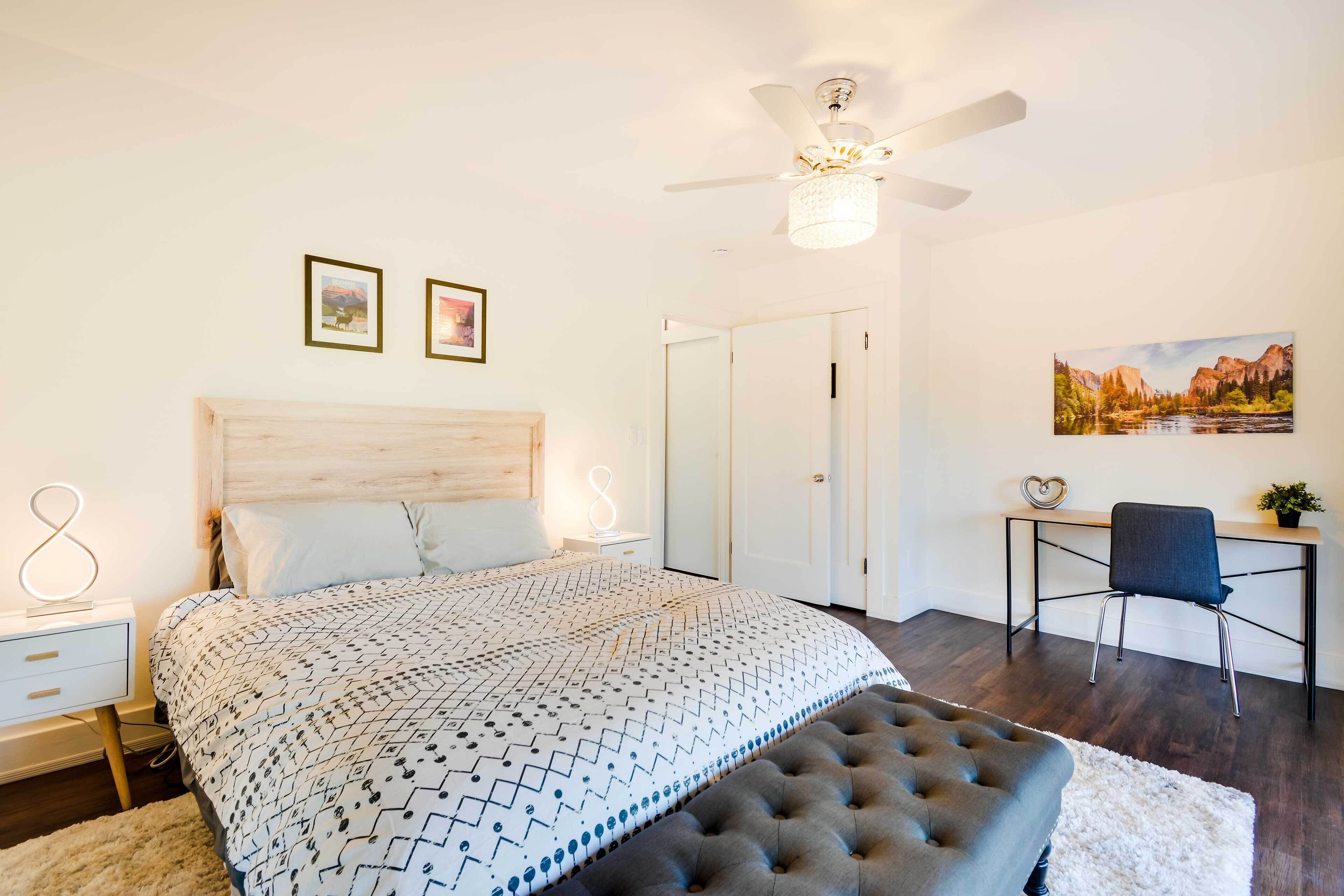 A bedroom with a bed, a desk, a chair, and a ceiling fan.