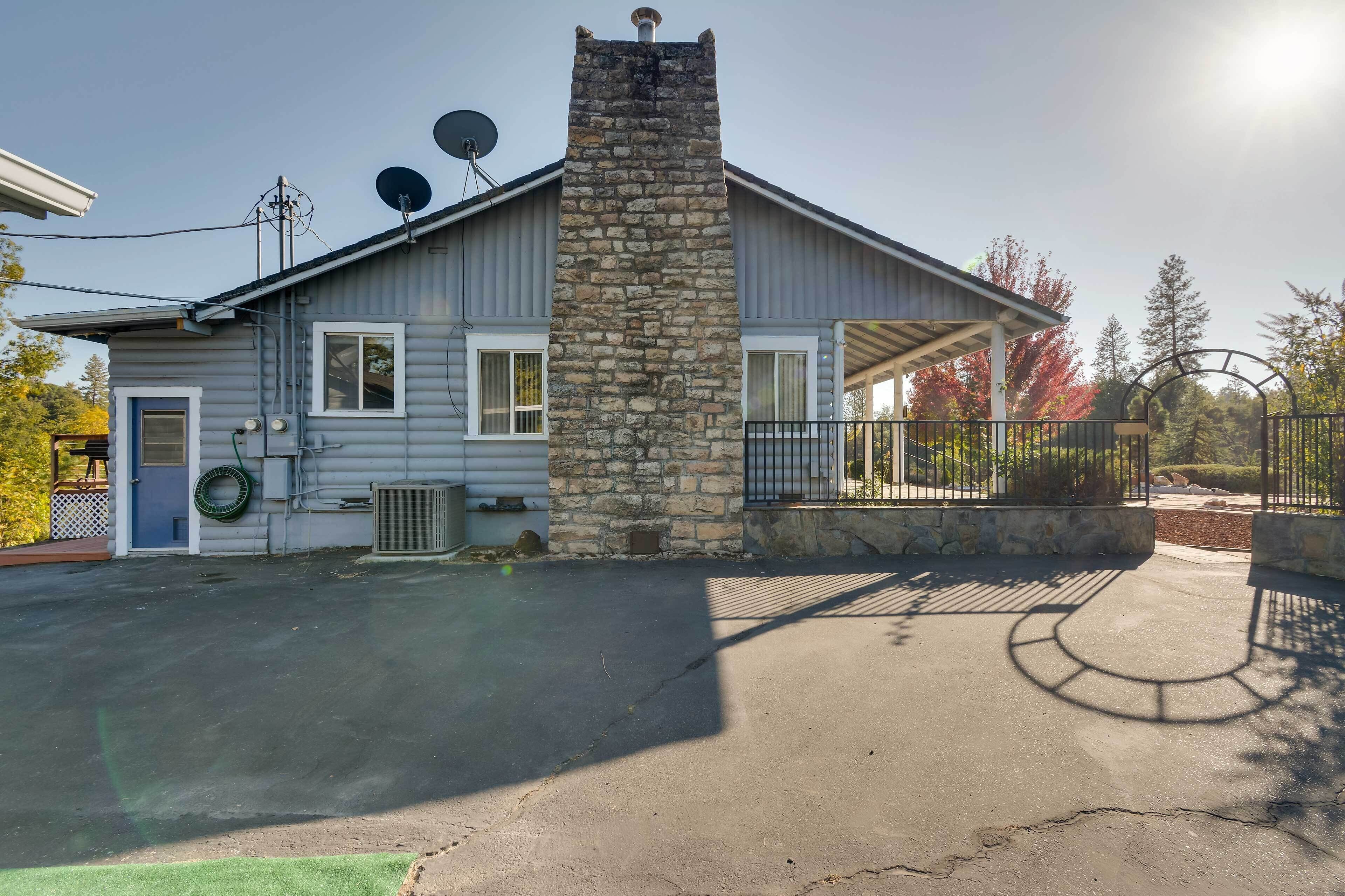 A two-story house with a stone chimney, satellite dishes, and a covered porch.