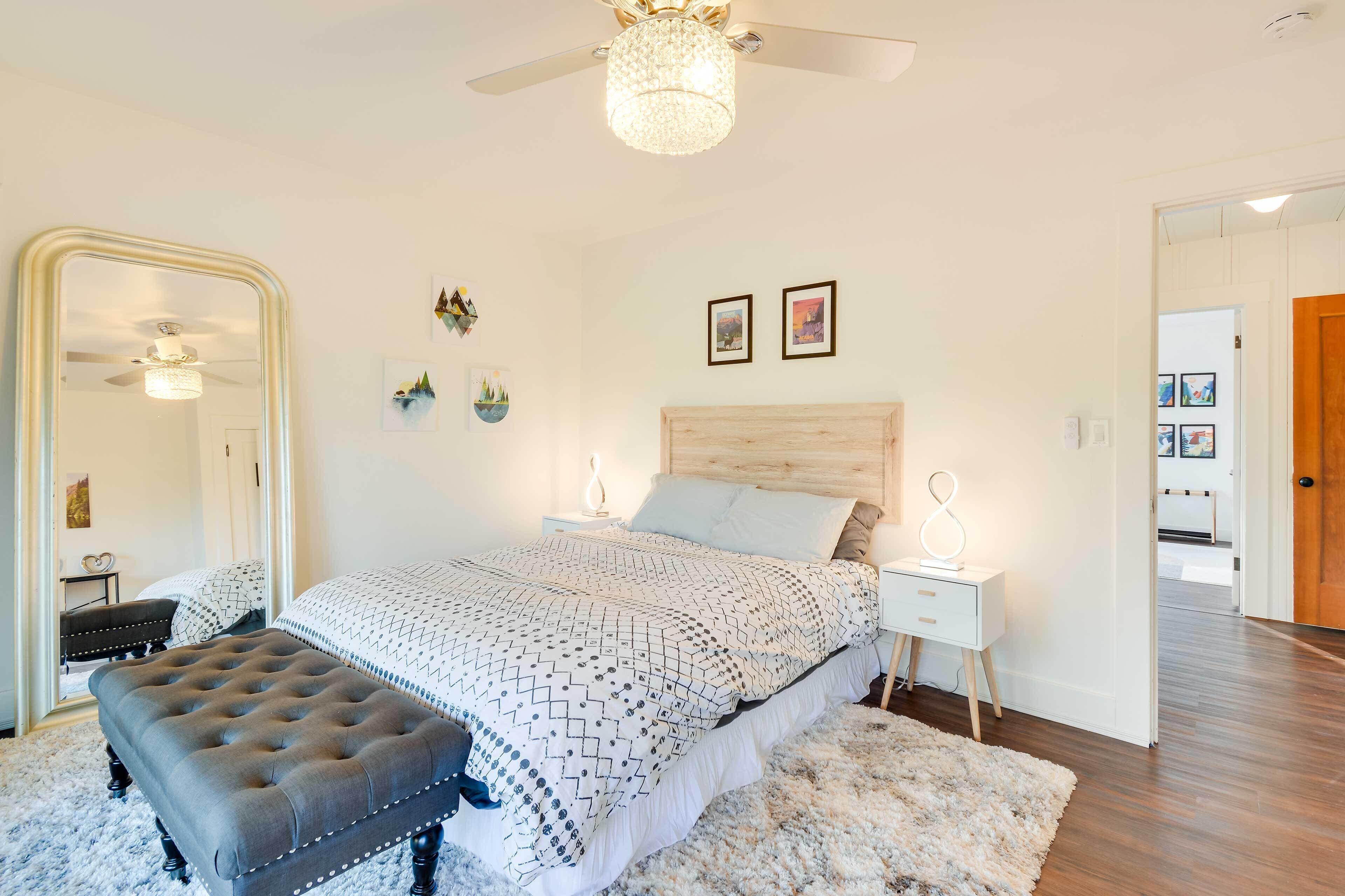 A bedroom with a bed, a large mirror, a ceiling fan, and a nightstand with a lamp.