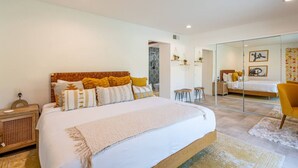 Een moderne slaapkamer met een groot bed, een nachtkastje, een spiegel en een stoel.