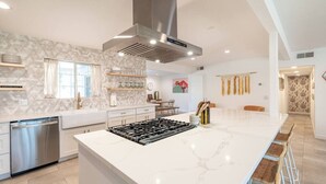 Een moderne keuken met een groot eiland, roestvrijstalen apparatuur en een decoratieve spatwand.