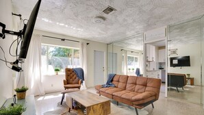 A modern living room with a leather sofa, a wooden coffee table, and a TV mounted on the wall. - Steps to Deerfield Beach: Home w/ Private Patio! (Deerfield Beach)