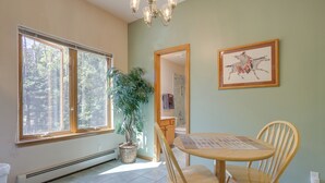 A room with a large window, a potted plant, a dining table with chairs, and a framed picture on the wall. - Pet-friendly Mountain Cabin in Taos County! (Amalia)