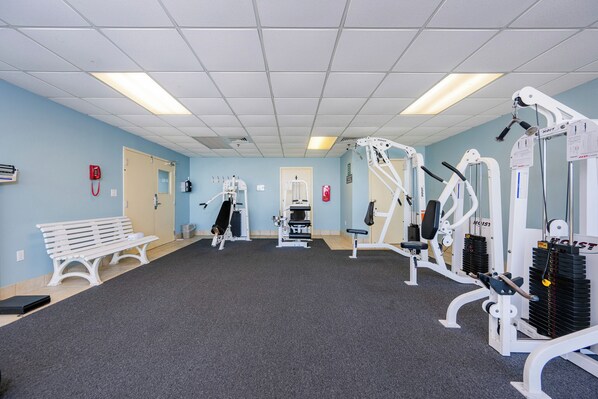 Un gimnasio con equipo de ejercicio, una banca y una puerta.