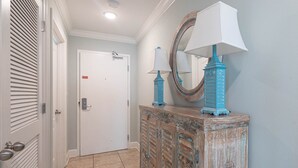 A hallway with a wooden cabinet, two wall-mounted lamps, and a mirror.