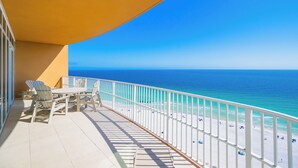 A balcony with a view of the ocean, a white railing, and a table with chairs. - Phoenix Gulf Towers 1701  Gulf-Front 4BR Condo (Orange Beach)