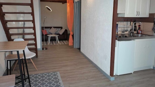 Une cuisine moderne avec des meubles blancs, un évier et un coin repas comprenant une table et des chaises.