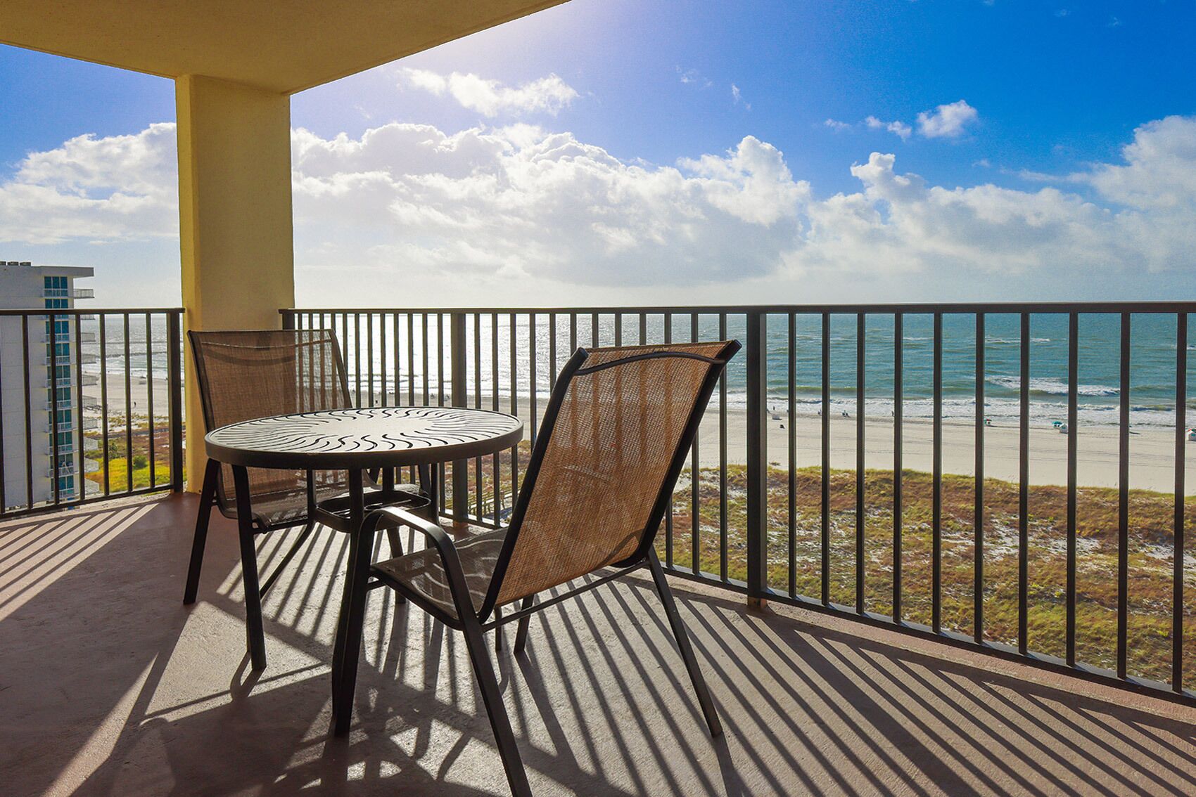 A balcony with a table and chairs overlooking a beach.