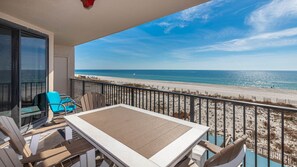 Een balkon met een tafel en stoelen, met uitzicht op een strand.