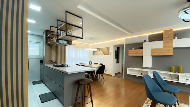 A modern kitchen with a central island, bar stools, and a dining area with a table and chairs. - Apartamento Morada do Sol Gramado (Gramado)