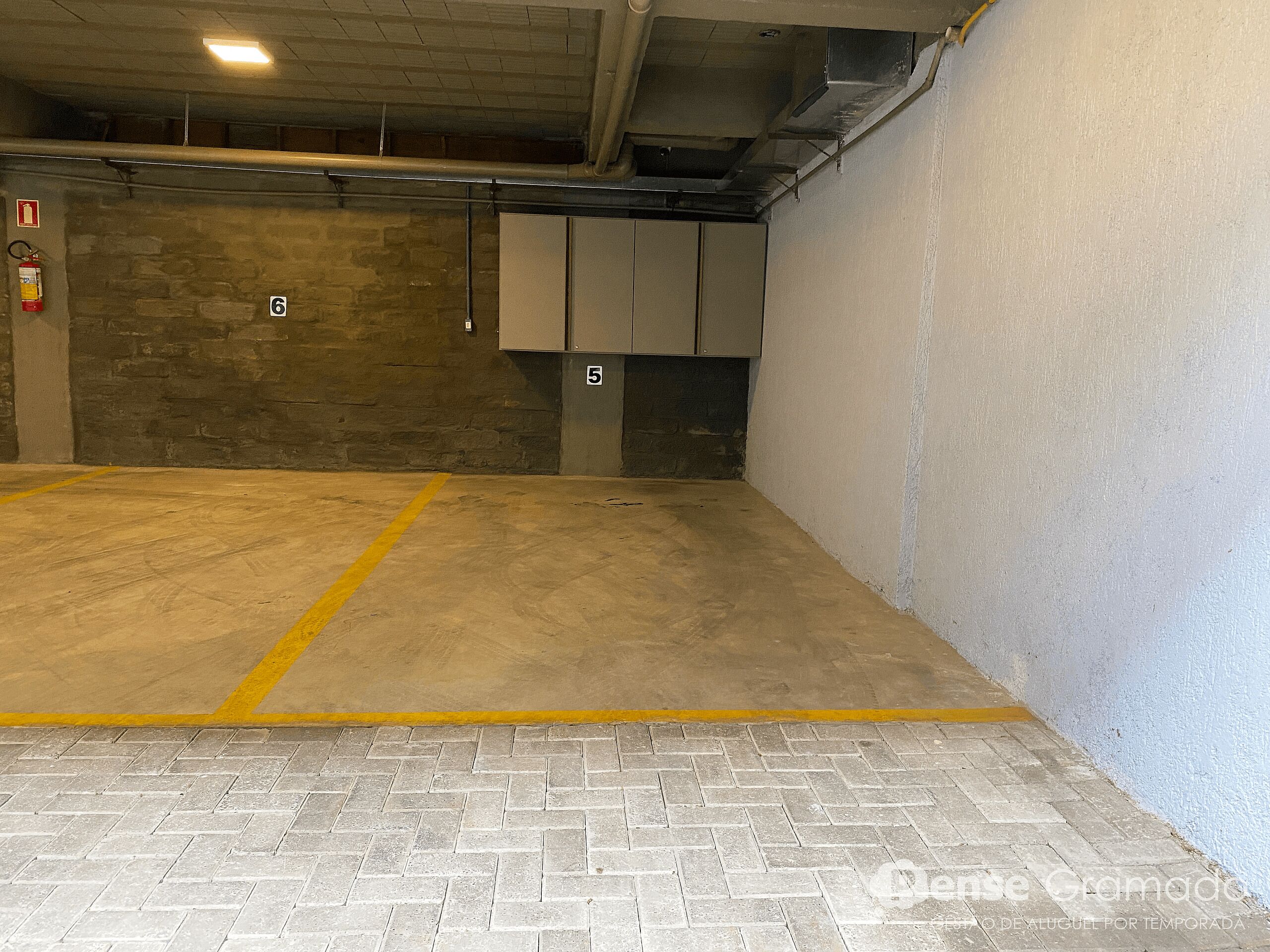 Un aparcamiento con plazas numeradas, un extintor y una manguera contra incendios en la pared.