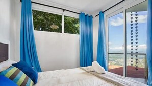 Een slaapkamer met een groot bed, witte beddengoed en blauwe gordijnen.