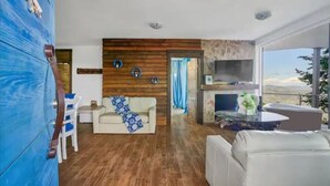 Een moderne woonkamer met een houten accentmuur, een open haard en uitzicht op de omgeving.