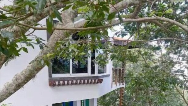 Een huis met twee verdiepingen, met een houten trap die naar een balkon leidt.