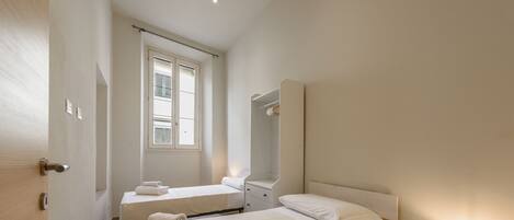 A bedroom with a bed, bedside table, and a window.