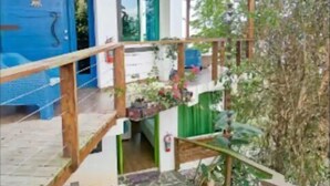 Un bâtiment avec une porte bleue, un escalier doté d’une rampe en bois et un sol recouvert de carreaux de pierre.