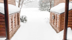 Una baita di legno con portico coperto e cortile innevato.
