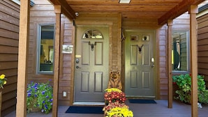 Un portico in legno con una statua di orso, due porte e fioriere.