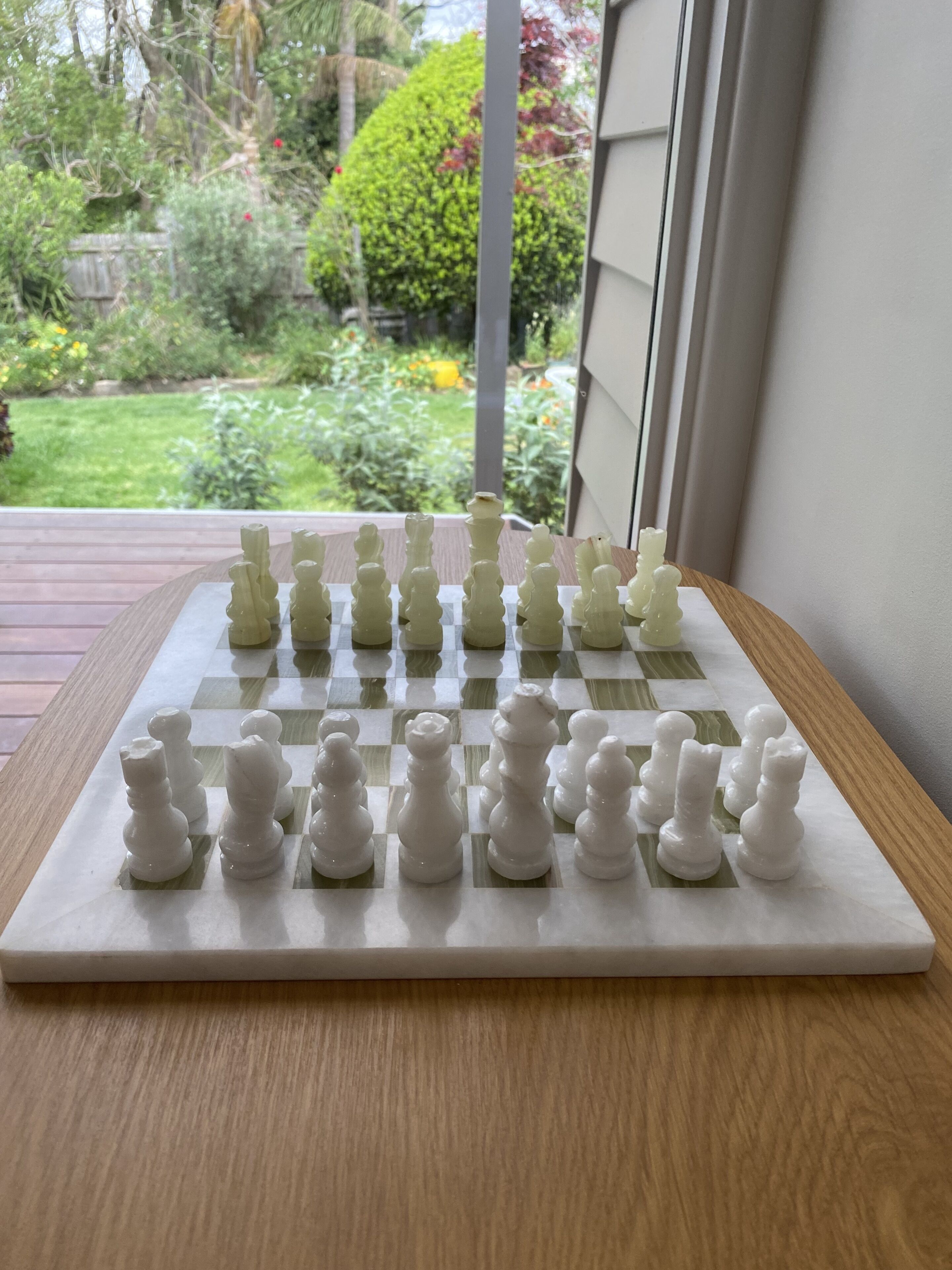 Una scacchiera su un tavolo di legno con vista su un giardino.