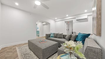 Un salon moderne avec un canapé d’angle, une table basse et un ventilateur de plafond.