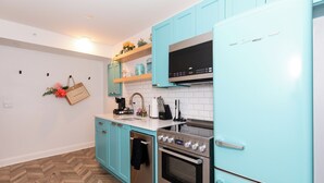 A kitchen with teal cabinets, a stainless steel refrigerator, and a double oven. - Chic Condo Near Cedar Point (Sandusky)