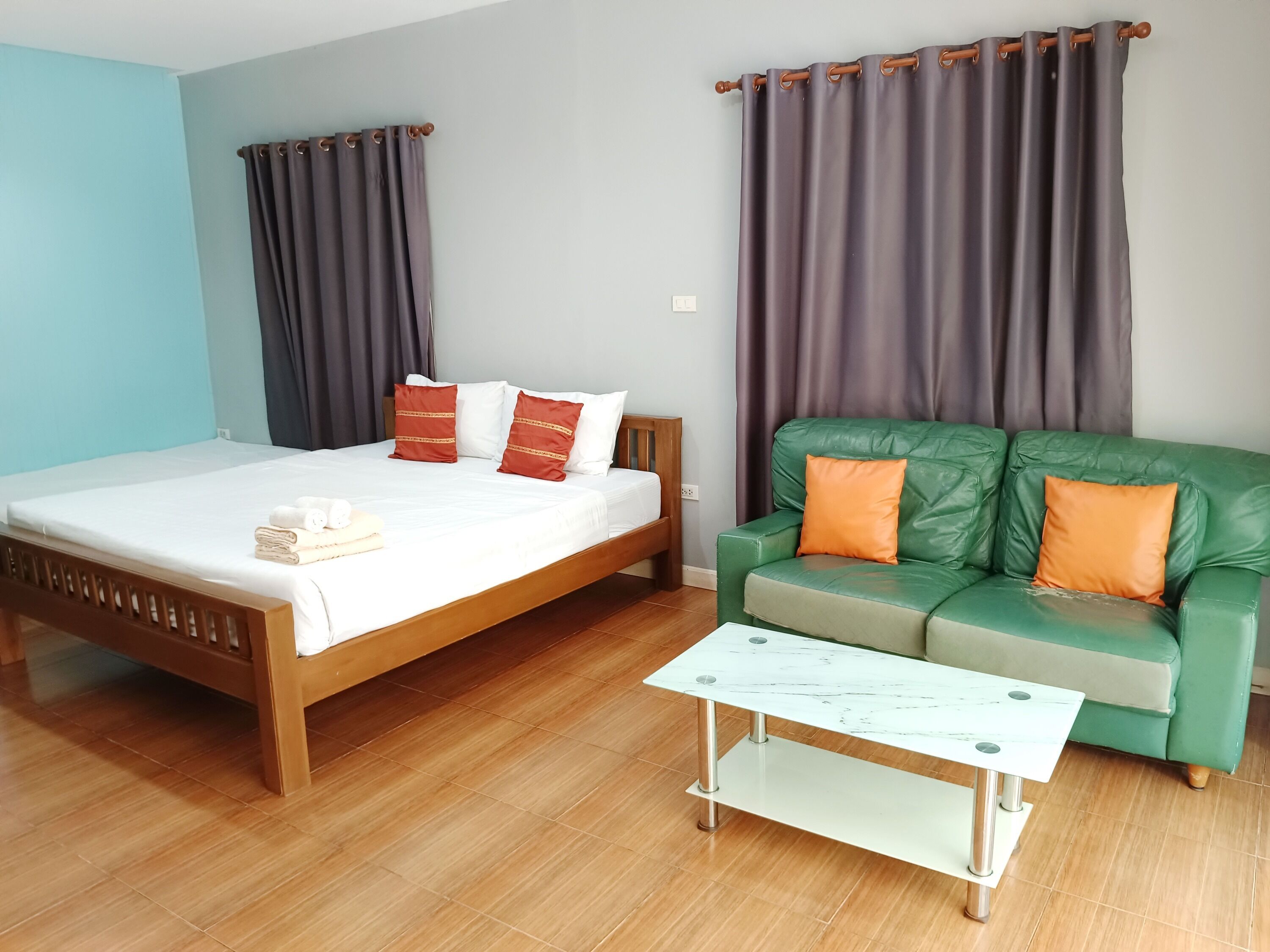 A bedroom with a bed, a green sofa, and a white coffee table.