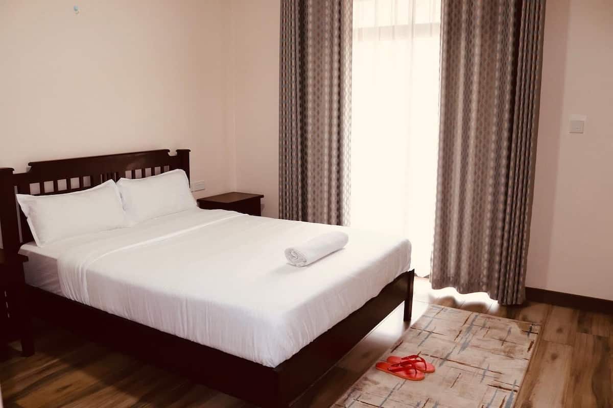 A neatly made bed with white linens, a wooden headboard, and a small bedside table.